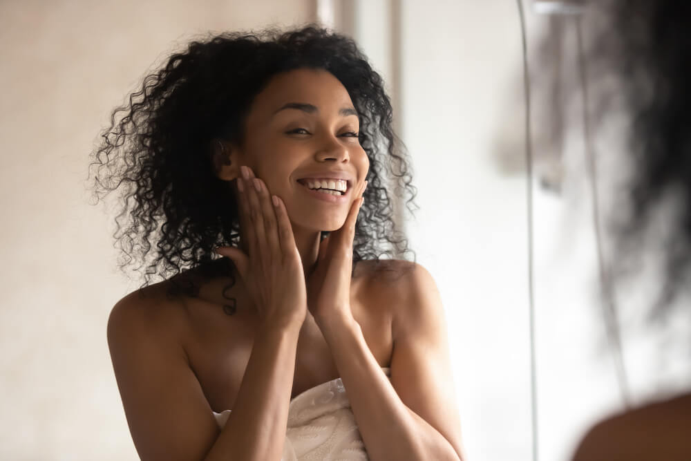 Tips to Increase the Lifespan of Your Injectables woman after her skincare routine looking in the mirror at her botox