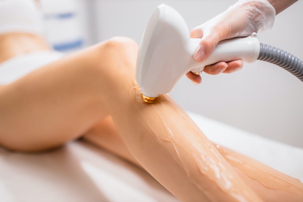 close-up woman’s legs while getting hair removal procedure in salon